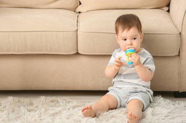 Evde yerde oturan nibbler ile Sevimli küçük çocuk