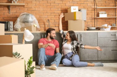 Yeni eve taşındıktan sonra yerde oturan mutlu genç çift