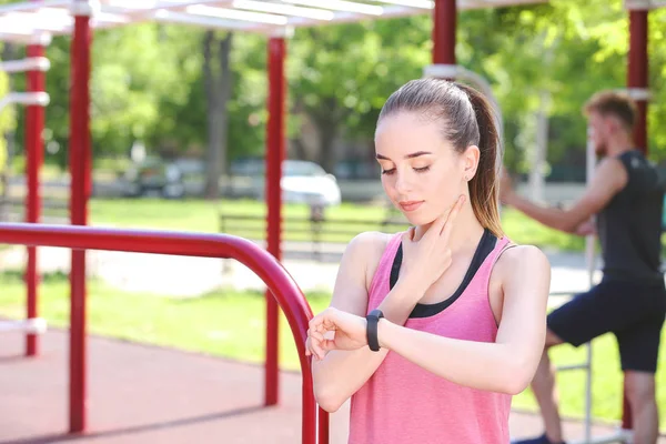 Sporty young woman checking her pulse outdoors — Stock Photo, Image