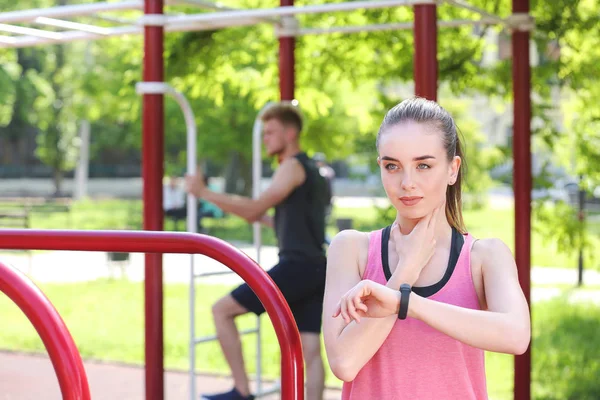 Sportos fiatal nő ellenőrzése ő impulzus kültéri — Stock Fotó