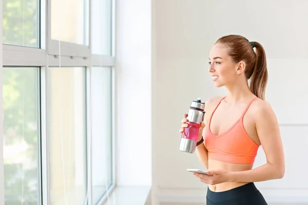 Sporty young woman drinking water in gym — Stock Photo, Image