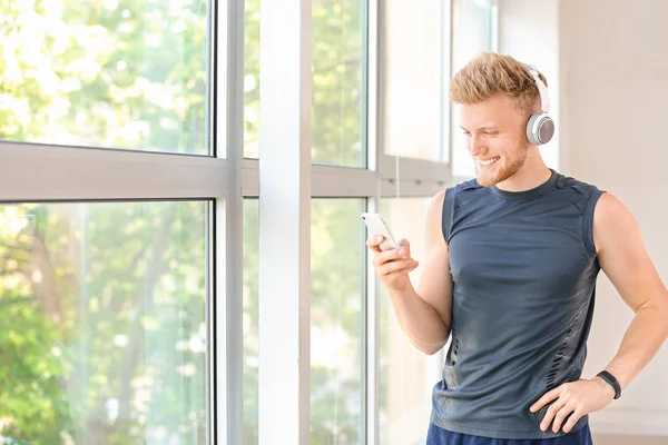 Sporty young man listening to music in gym — Stock Photo, Image