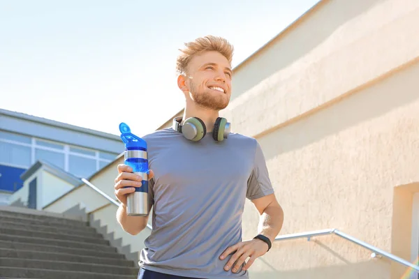 Sporty young man drinking water after training outdoors — Stock Photo, Image