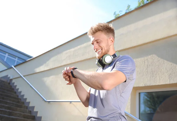 Sporty young man checking his pulse outdoors