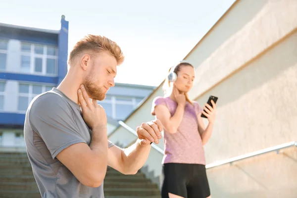 Sporty young people checking pulse outdoors — Stock Photo, Image