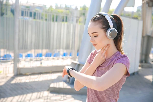 Sporty young woman checking her pulse outdoors — Stock Photo, Image