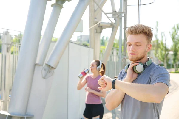 Sporty young man checking his pulse outdoors — Stock Photo, Image