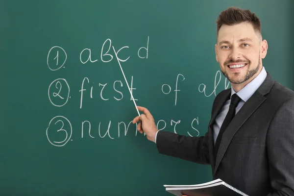 Beau professeur masculin près du tableau noir en classe — Photo