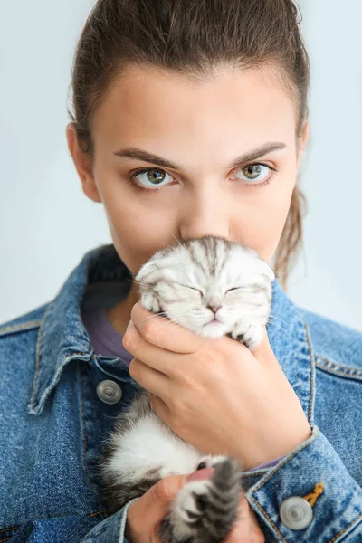 Hermosa mujer joven con lindo gatito en fondo claro — Foto de Stock