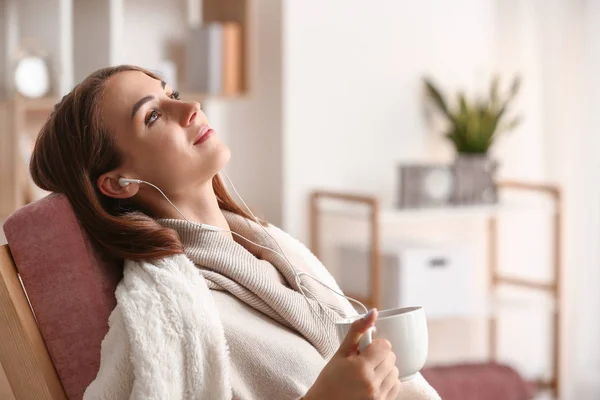 Hermosa joven bebiendo té mientras escucha música en casa — Foto de Stock