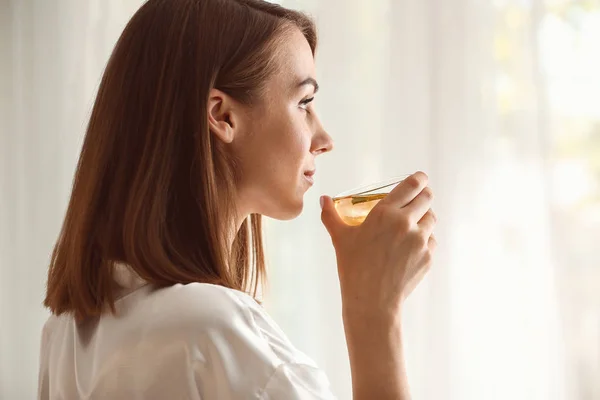 Красива молода жінка п'є чай вдома — стокове фото