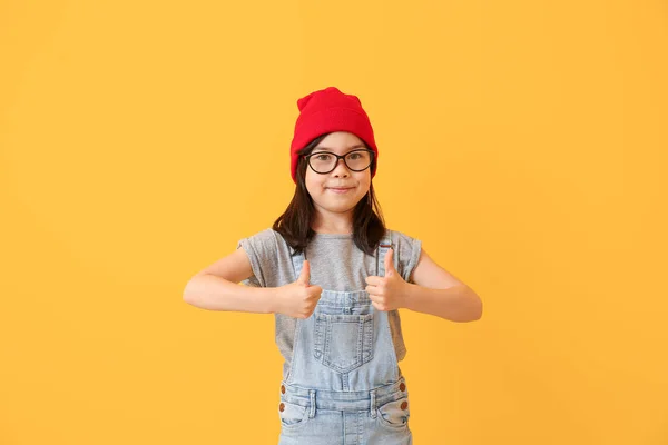 Portrait of stylish little girl showing thumb-up gesture on color background — Stock Photo, Image