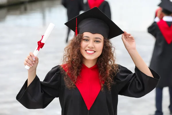 Felice studente afro-americano in accappatoio e con diploma all'aperto — Foto Stock