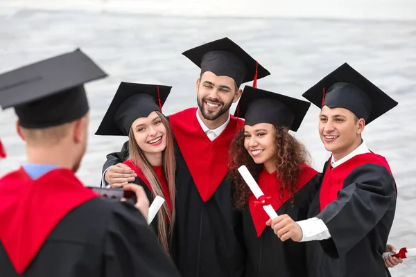 Boldog diákok Bachelor köpenyekben és diplomák szabadban — Stock Fotó
