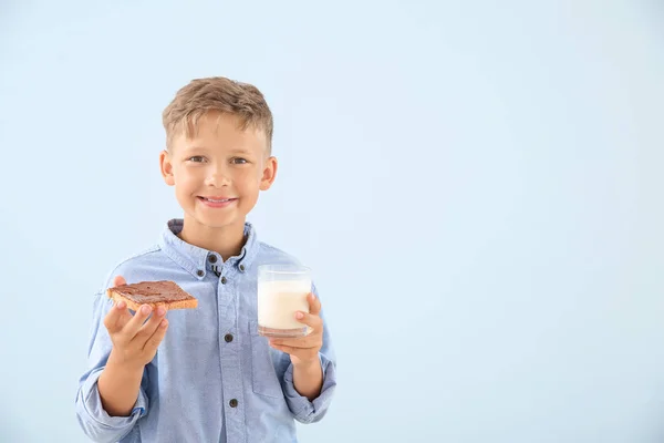 Zabawny mały chłopiec z smacznym tosty i szklanką mleka na tle koloru — Zdjęcie stockowe
