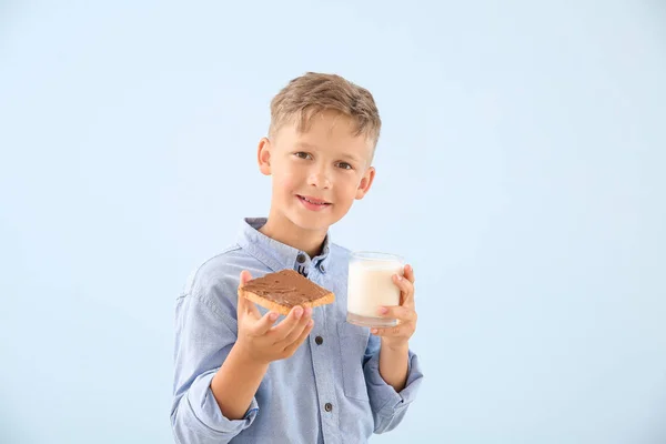 Funny little boy with tasty toast and glass of milk on color background — Stock Photo, Image