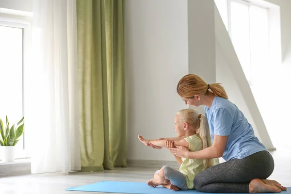 Mother helping her little girl with yoga position at home — Stock Photo, Image