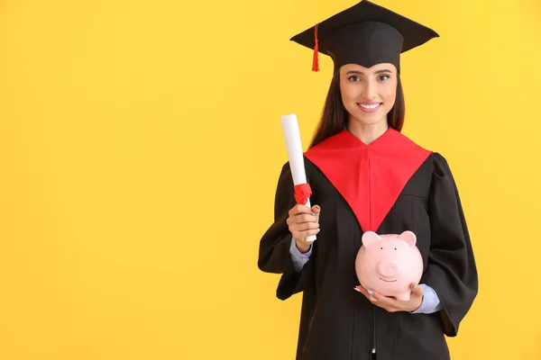 Vrouwelijke afgestudeerd met diploma en Piggy Bank op kleur achtergrond. Collegegeld kosten concept — Stockfoto