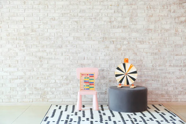 Cadeira e pufe com brinquedos perto da parede de tijolo no quarto das crianças — Fotografia de Stock