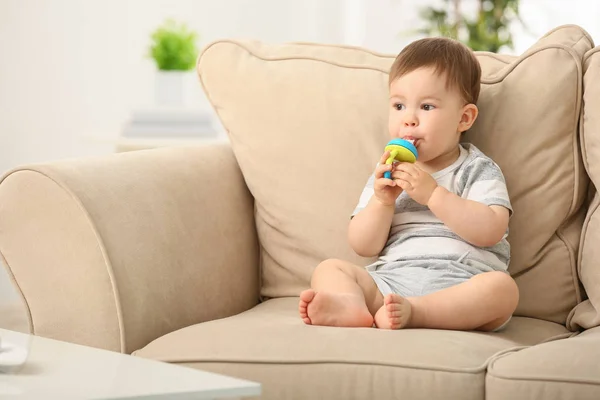 Lindo niño pequeño con mordedor sentado en el sofá en casa — Foto de Stock