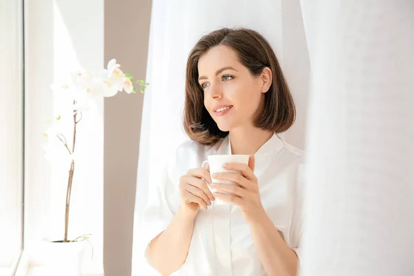 Ранок красивої молодої жінки п'є каву біля вікна — стокове фото