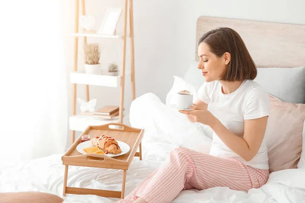Schöne junge Frau frühstückt im Bett — Stockfoto