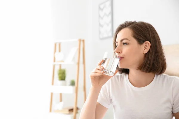 Mañana de hermosa mujer joven bebiendo agua en el dormitorio —  Fotos de Stock