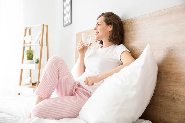 Morning of beautiful young woman drinking water in bedroom — Stock Photo, Image