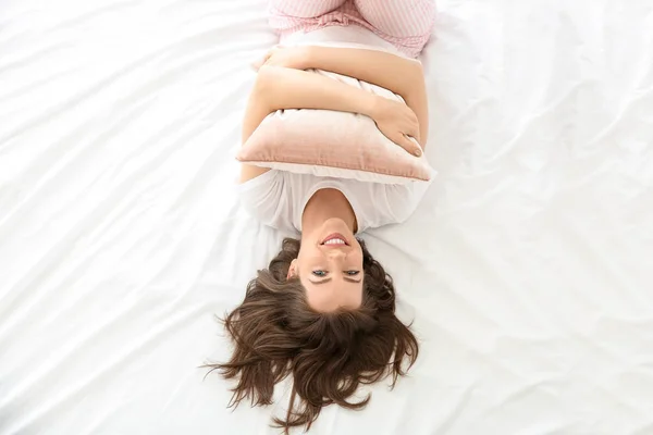 Mañana de hermosa joven con almohada acostada en la cama —  Fotos de Stock