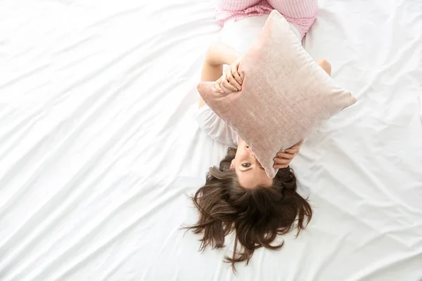 Ochtend van mooie jonge vrouw met kussen liggend op bed — Stockfoto