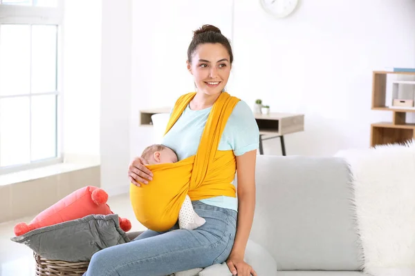 Young mother with little baby in sling at home — Stock Photo, Image
