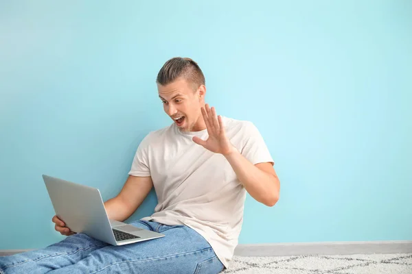 Male blogger with laptop sitting near color wall — Stock Photo, Image