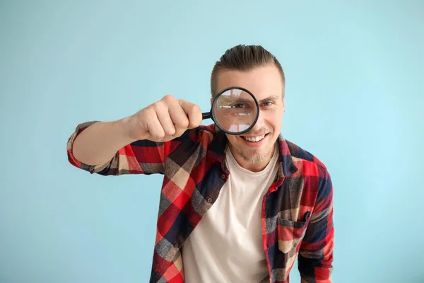 Jeune homme avec loupe sur fond de couleur — Photo