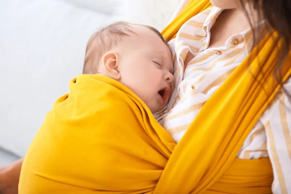 Joven madre con un pequeño bebé en cabestrillo en casa, primer plano —  Fotos de Stock