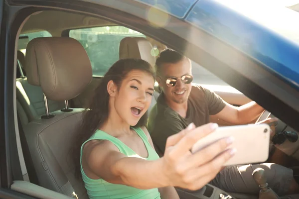 Feliz joven pareja tomando selfie en coche — Foto de Stock