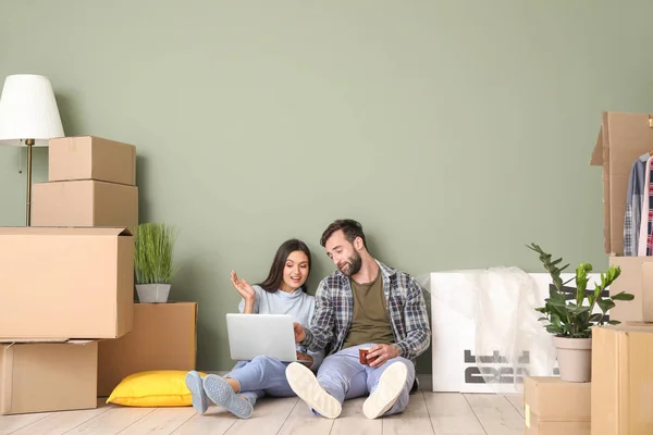 Молодая пара с картонными коробками и ноутбуком после переезда в новый дом — стоковое фото