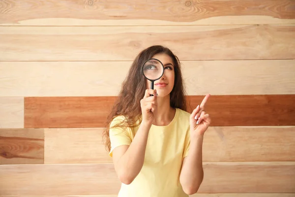 木製の背景に虫眼鏡を持つ若い女性 — ストック写真