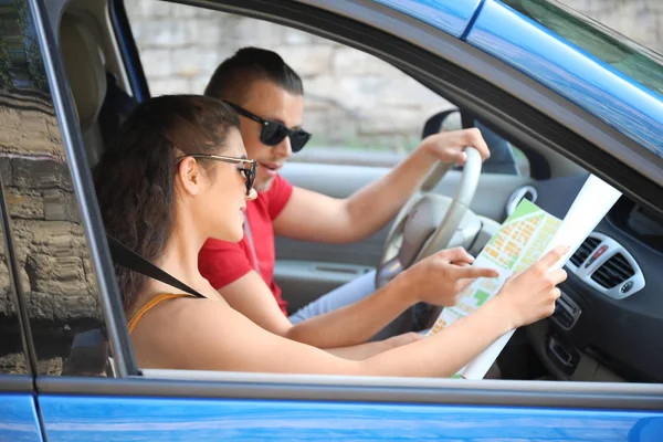 Happy young couple with road map traveling by car — Stock Photo, Image