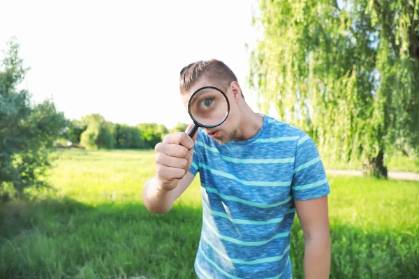 Giovane uomo con lente d'ingrandimento studiare la natura all'aperto — Foto Stock