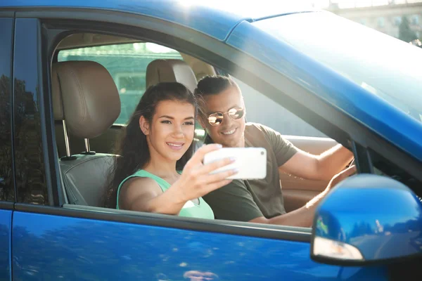 Feliz joven pareja tomando selfie en coche — Foto de Stock