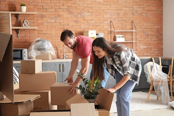 Young couple unpacking things after moving into new house — Stock Photo, Image