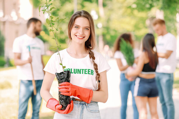 Female volunteer with young tree outdoors