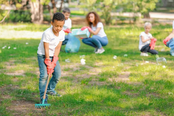 Little African-American volunteer gathering garbage in park — Stock Photo, Image