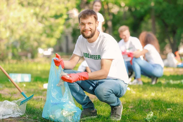 Male volunteer gathering garbage in park — Stock Photo, Image
