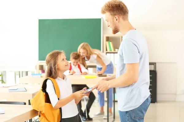 Pai dando a menina um livro em sala de aula — Fotografia de Stock