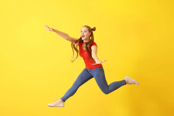 Jumping young woman against color background — Stock Photo, Image