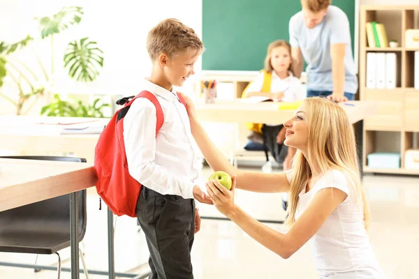 Moeder geeft kleine jongen appel in het klaslokaal — Stockfoto