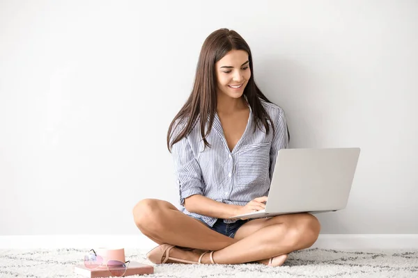 Female blogger with laptop sitting near white wall — Stock Photo, Image