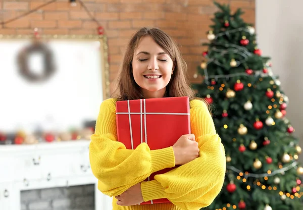 Happy young woman with Christmas gift at home — Stock Photo, Image
