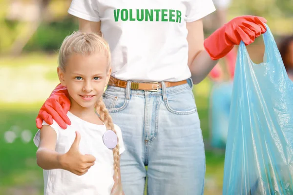 Pequeño voluntario con la mujer recogiendo basura en el parque —  Fotos de Stock